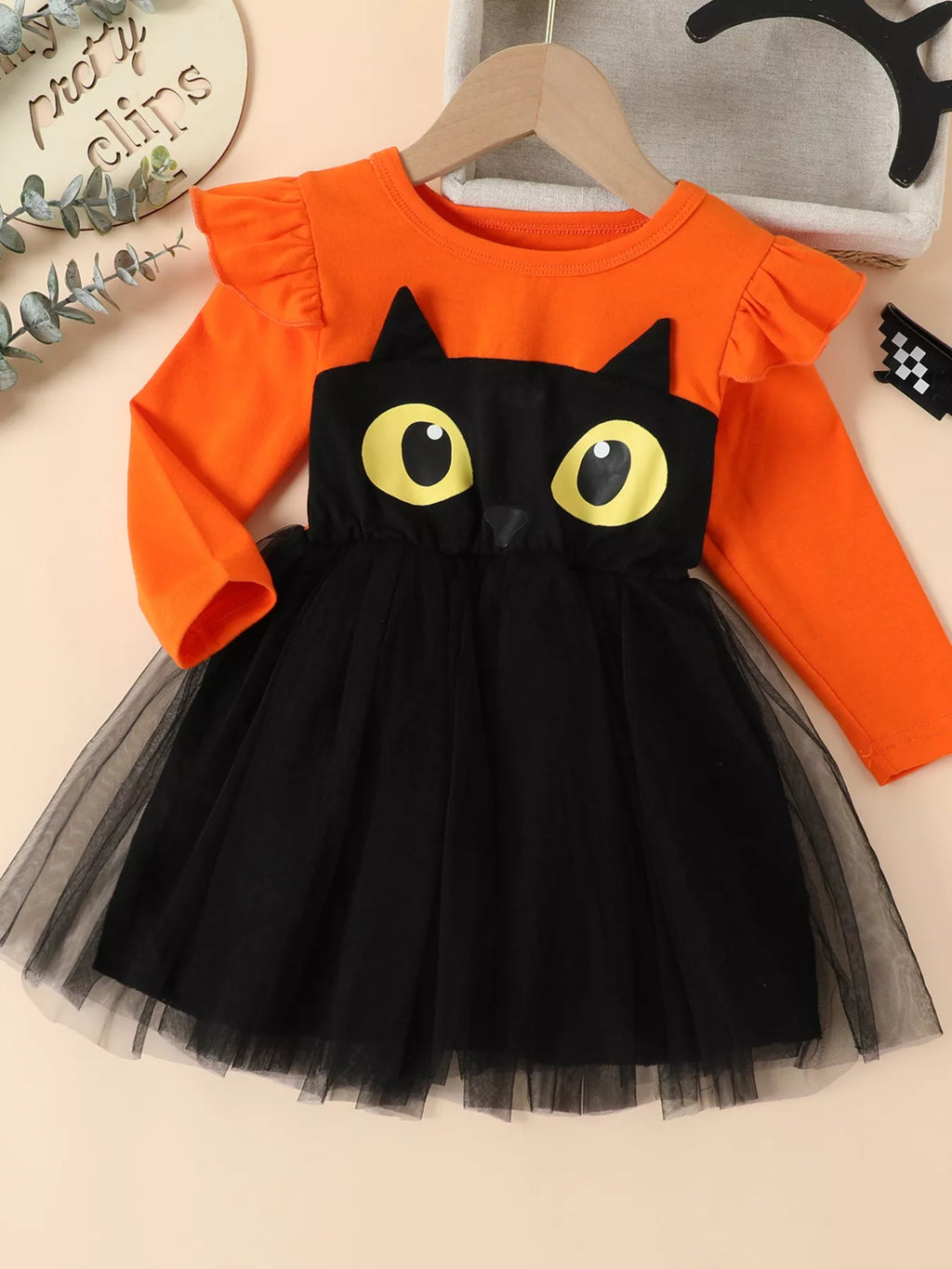 Front view of an orange long-sleeve black-cat dress with yellow eyes and a black tulle skirt.