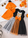 Orange hooded cape with black pom-pom paired with a black, orange and white tulle Halloween dress.