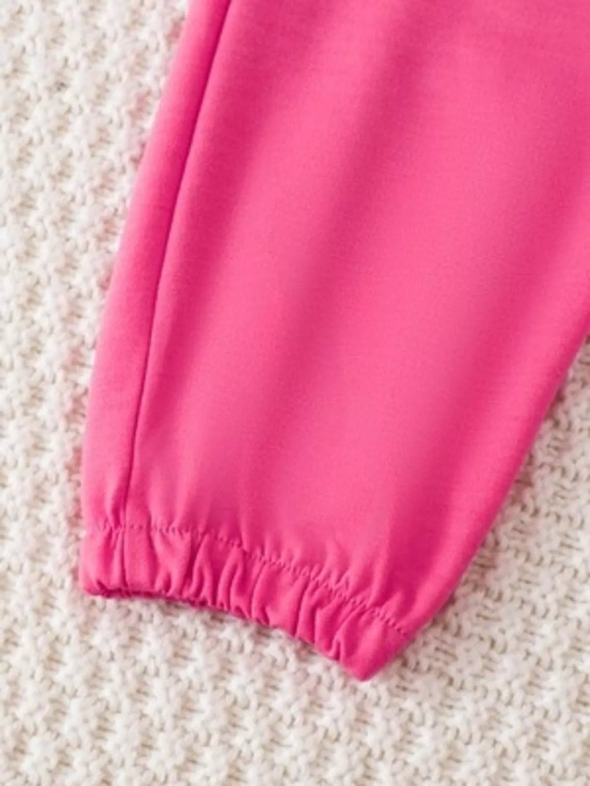 Close-up of the bright pink jogger pants' elastic ankle cuff.