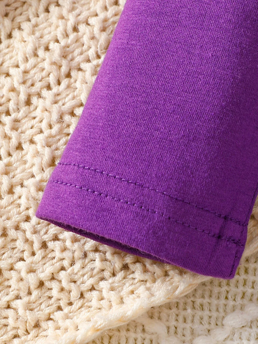 Close-up of the purple top's sleeve hem stitching.