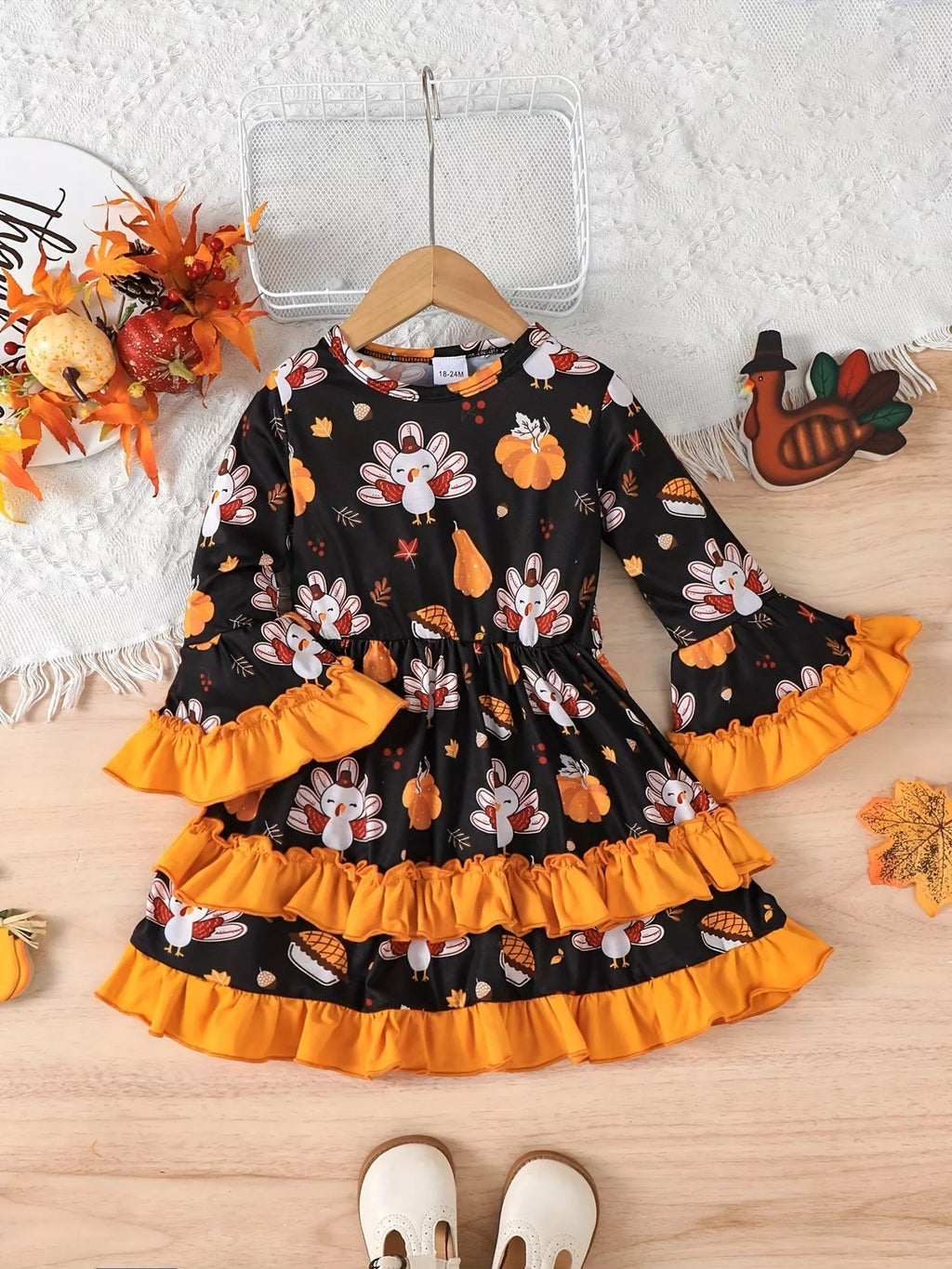 Children’s black turkey-print long-sleeve dress with orange ruffle trim displayed flat