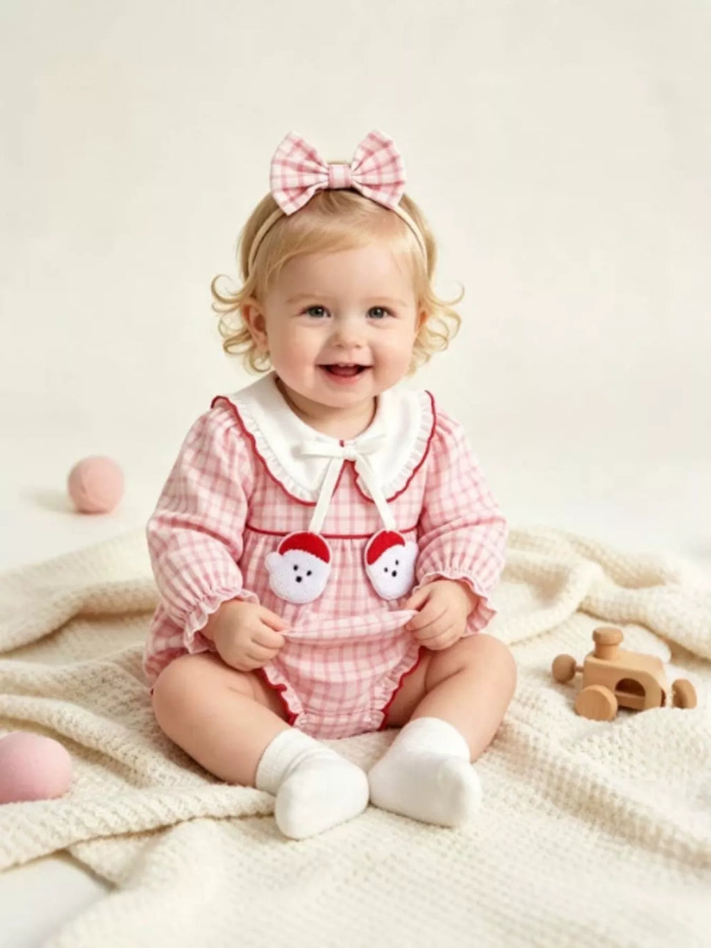 Children’s pink gingham long-sleeve bodysuit with a white collar and matching bow headband worn by a child