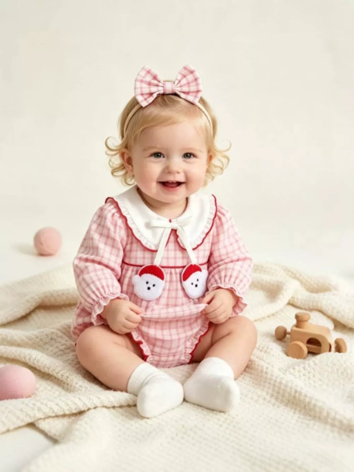 Children’s pink gingham long-sleeve bodysuit with a white collar and matching bow headband worn by a child