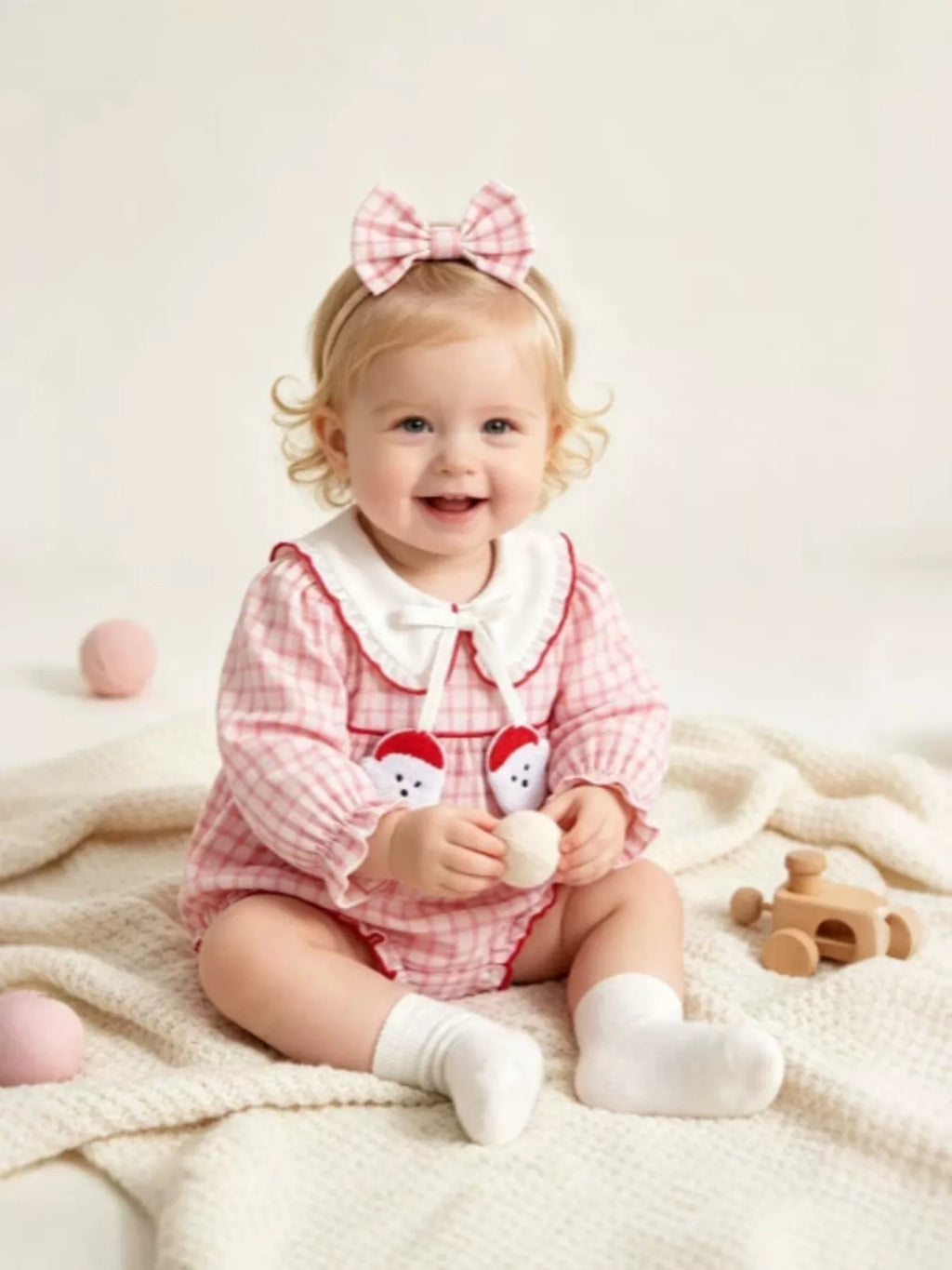 Children’s pink gingham long-sleeve bodysuit with a white collar and matching bow headband worn by a child