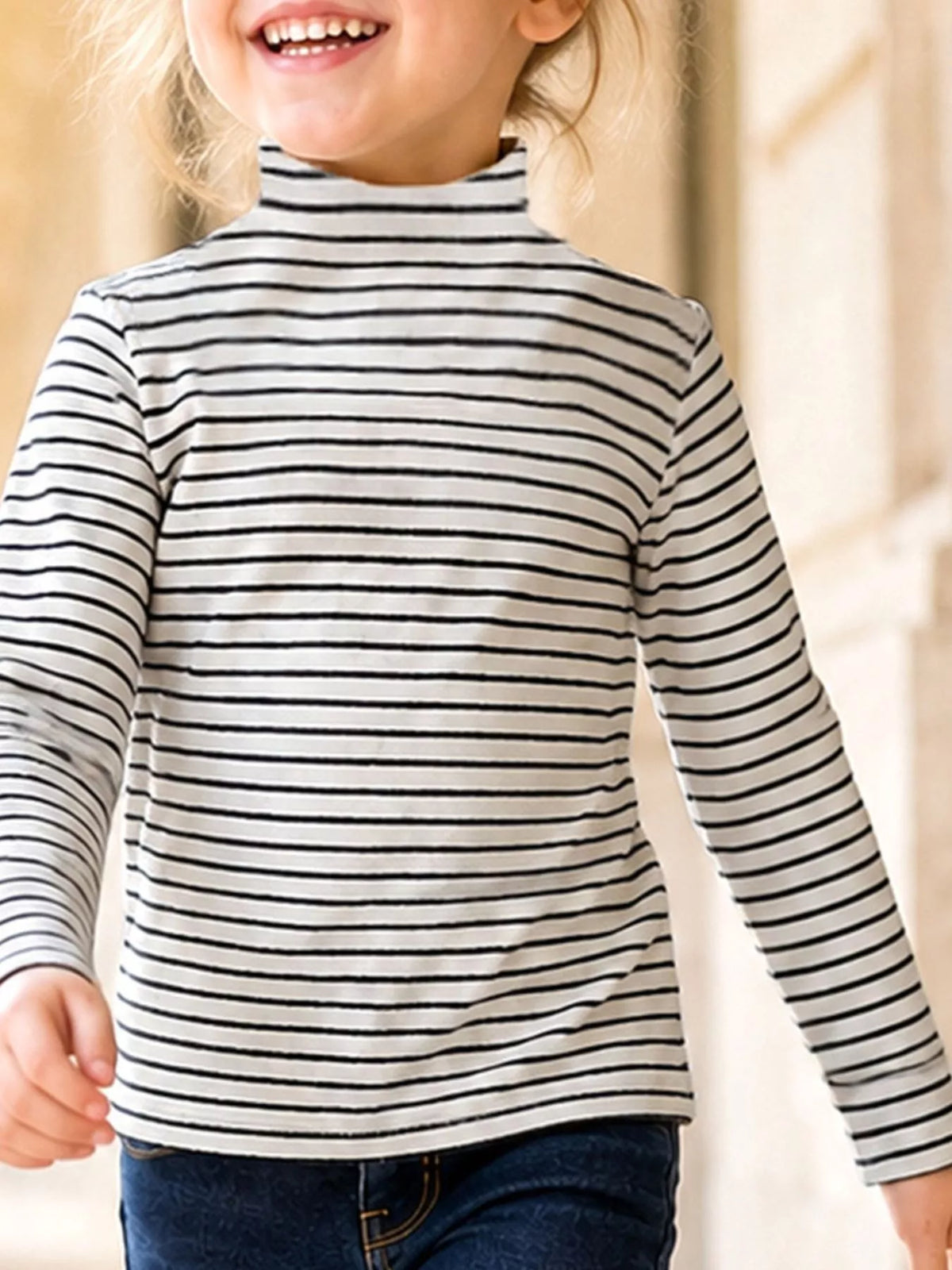 Child wearing a cream and black striped long-sleeve turtleneck top.