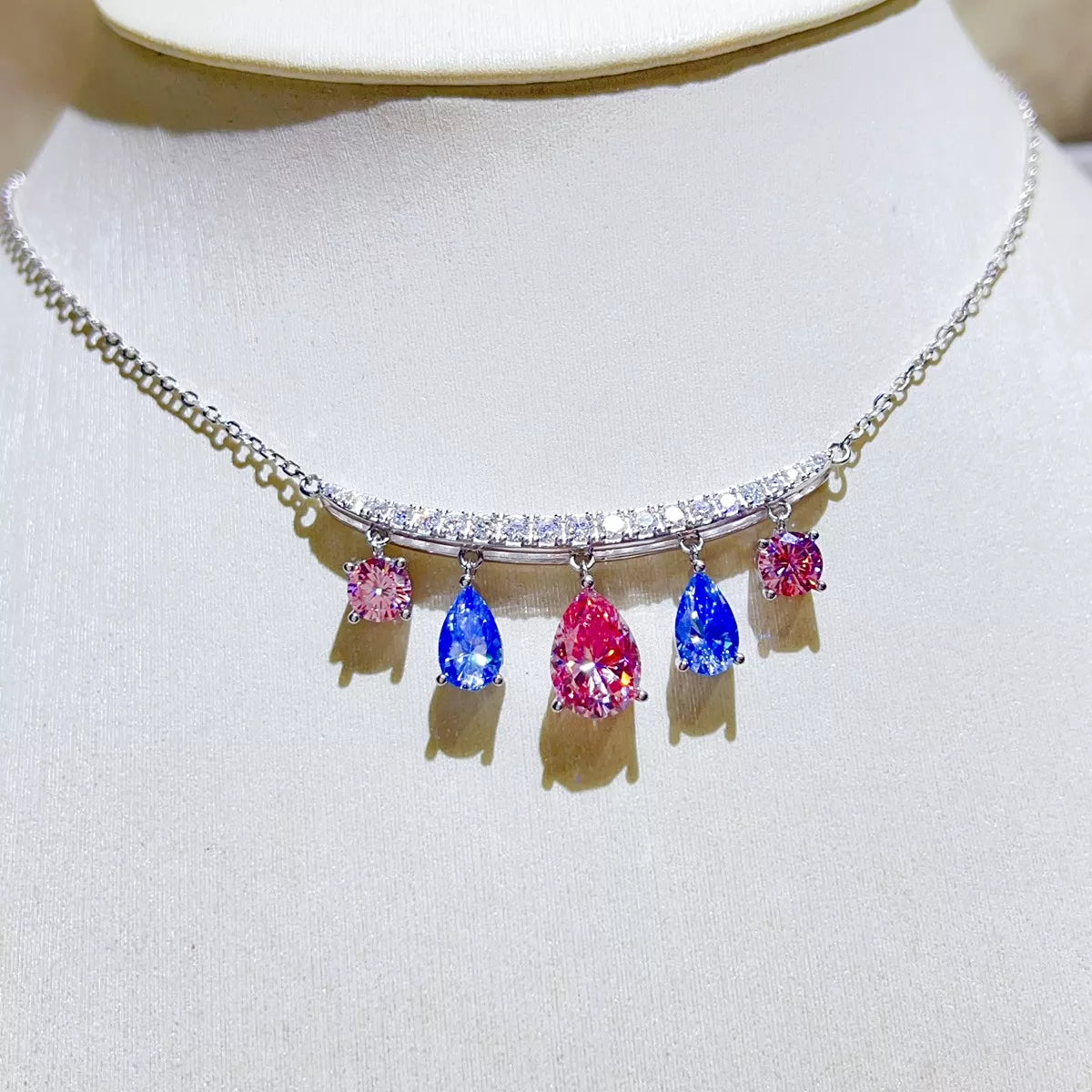 Silver-tone necklace with blue and pink teardrop stone pendants — detail view