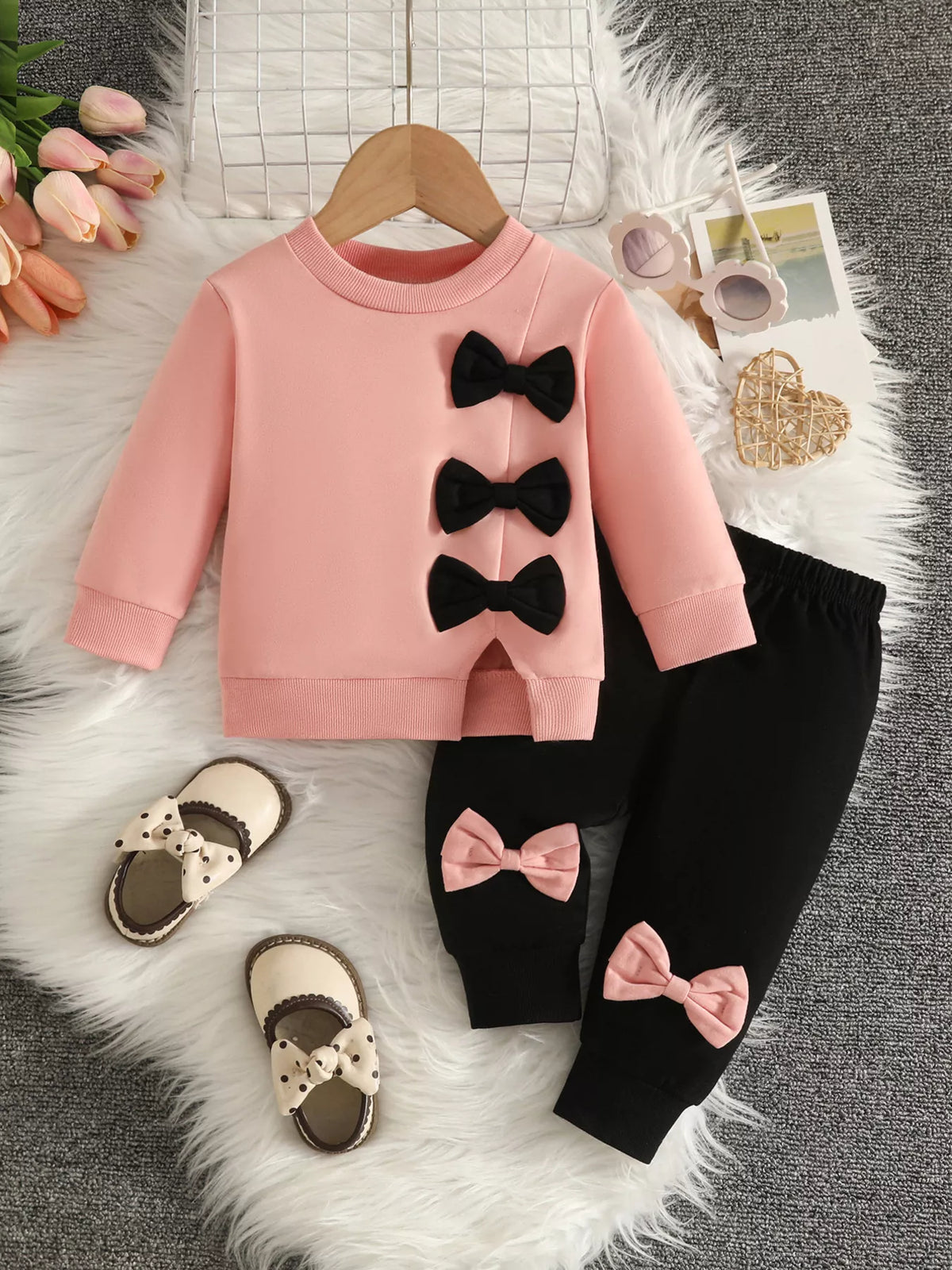 Blush pink top with black bow appliques and black pants with pink bows.
