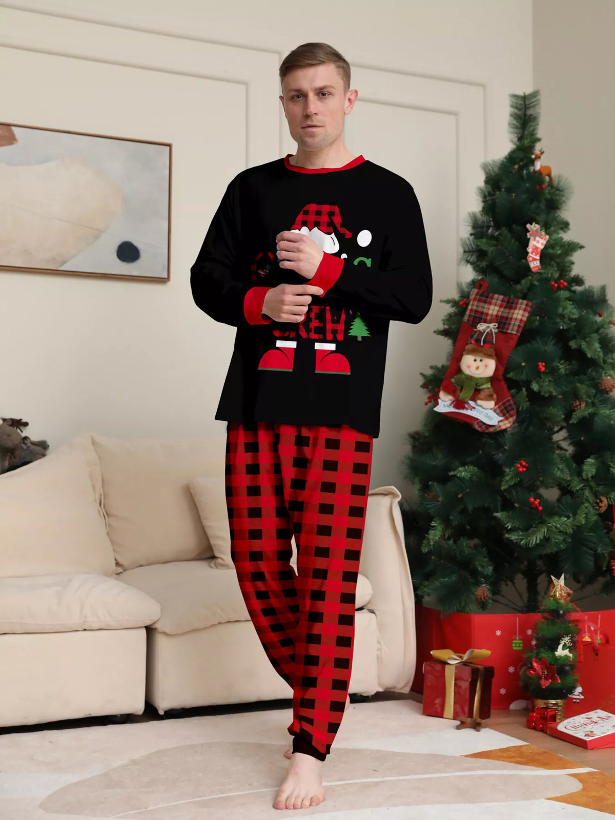 Man modeling the black Christmas graphic top and red plaid pajama pants.