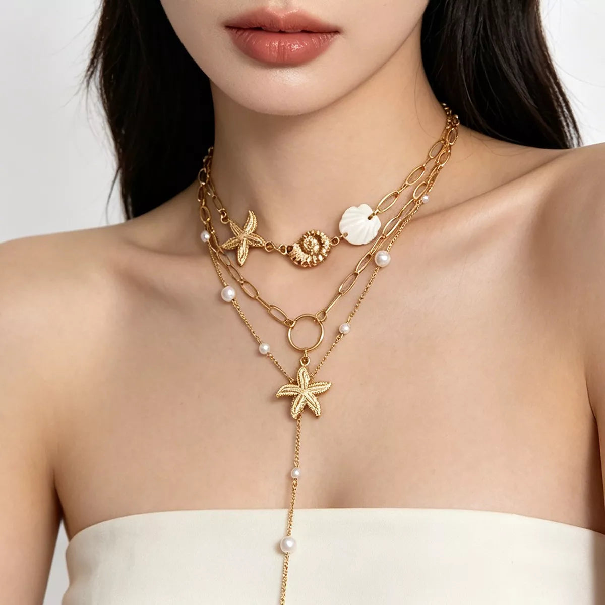Layered gold-tone necklaces with starfish and shell charms