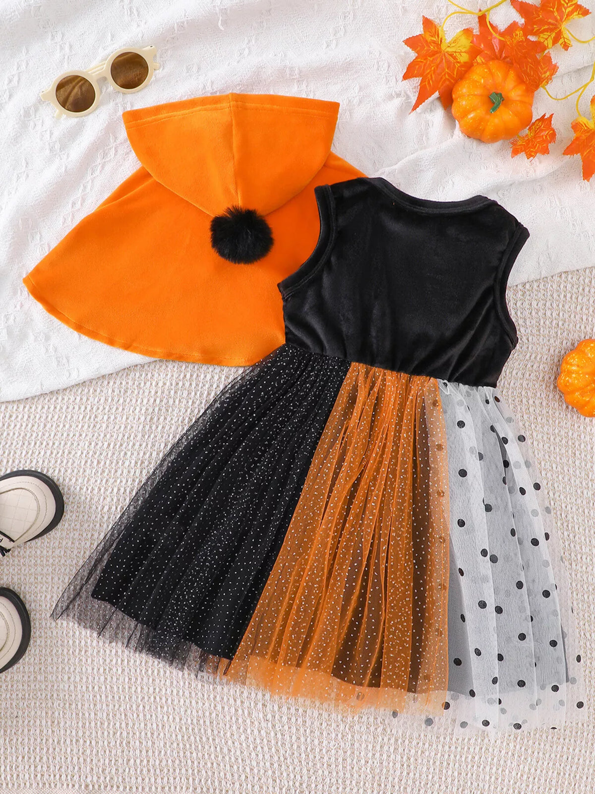Back flat lay of the orange hooded cape and black, orange and white tulle dress.