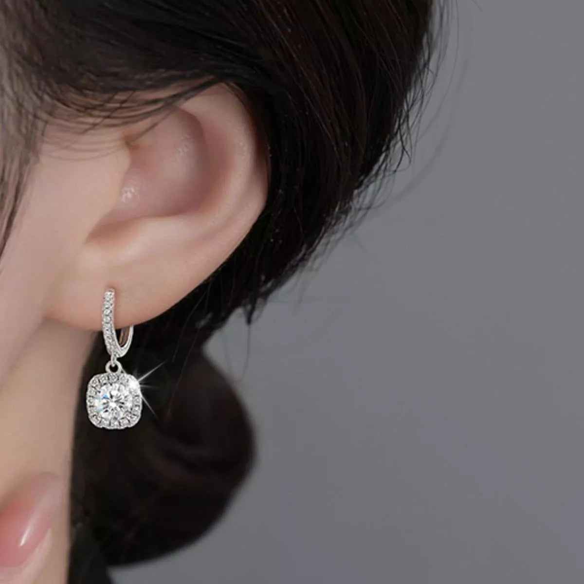 Silver-tone hoop earrings with square halo stone drops worn on a model