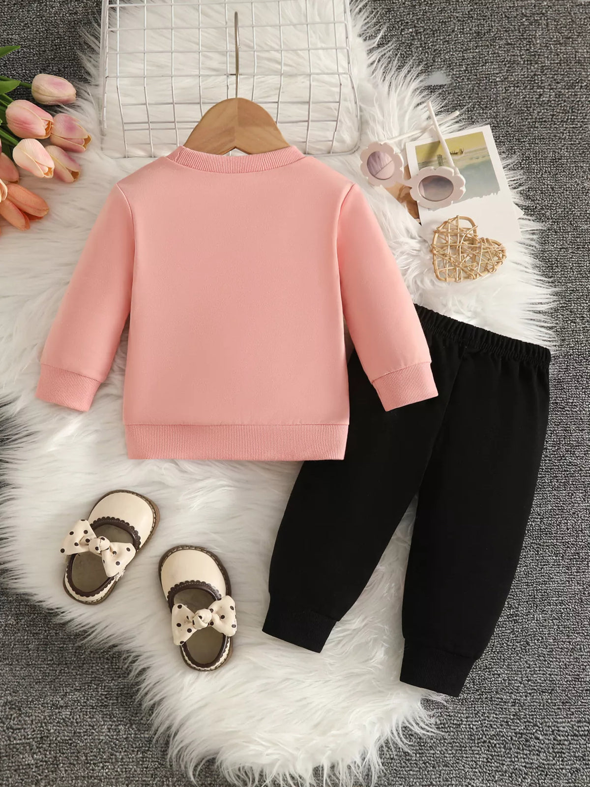 Back flat lay of the blush pink top and black pants.