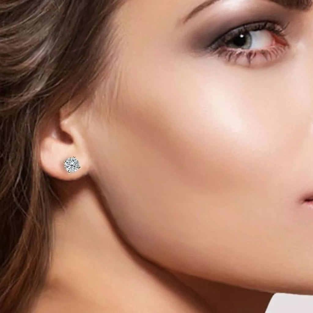 Gold-tone stud earrings with round clear stones worn on a model
