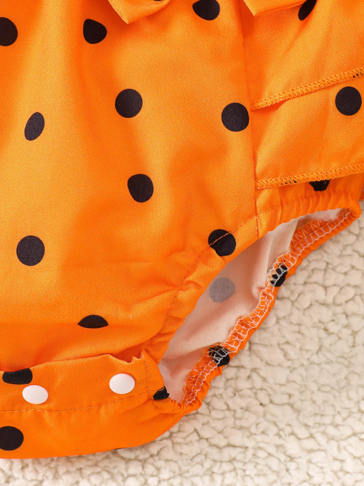Close-up of the orange polka-dot romper's gathered leg opening.