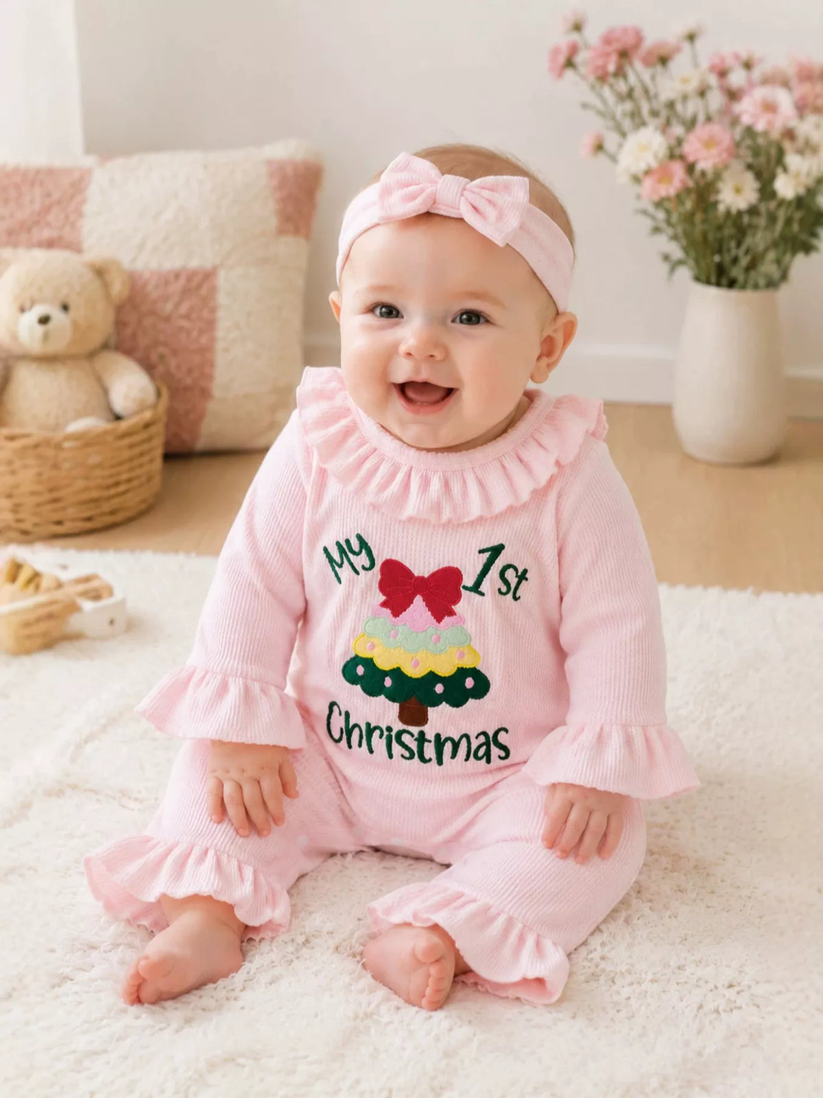 Seated baby wearing the pink Christmas graphic romper and bow headband.