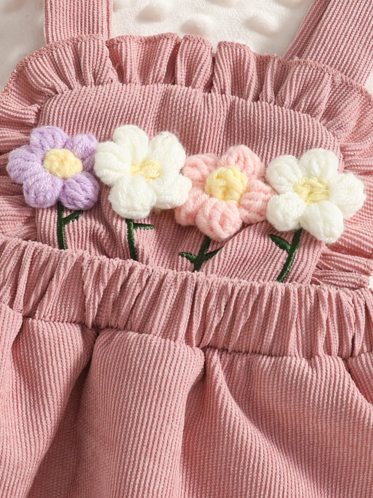 Close-up of the dusty pink skirt's fabric flowers, ruffled bib and gathered waist.