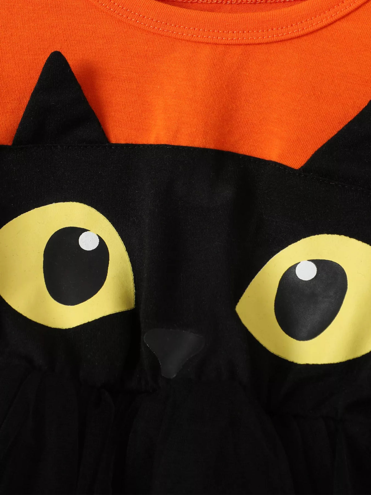 Close-up of the black cat face and large yellow eyes on the orange Halloween dress.