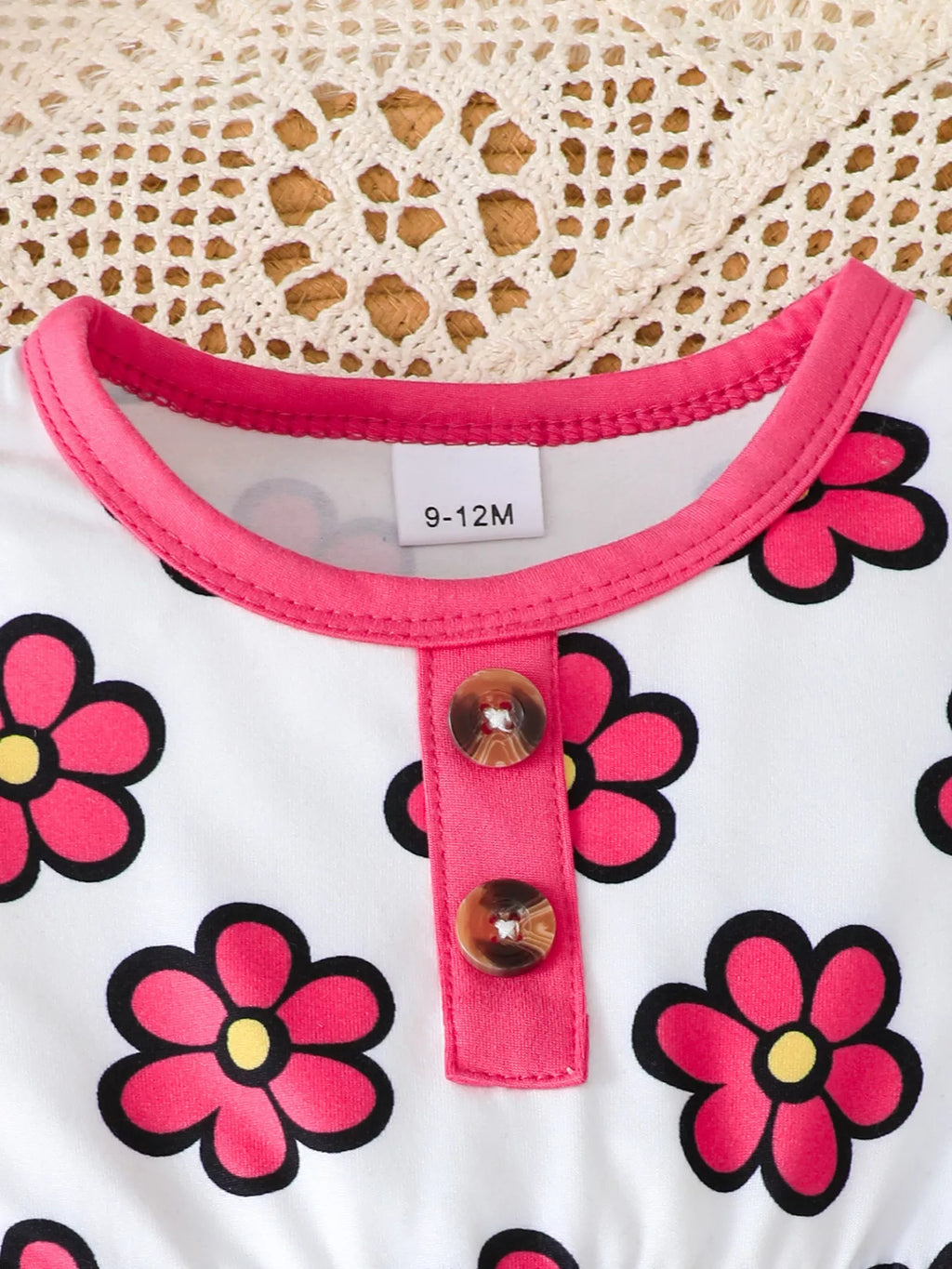 Close-up of the pink-trimmed neckline and button placket on the floral top.