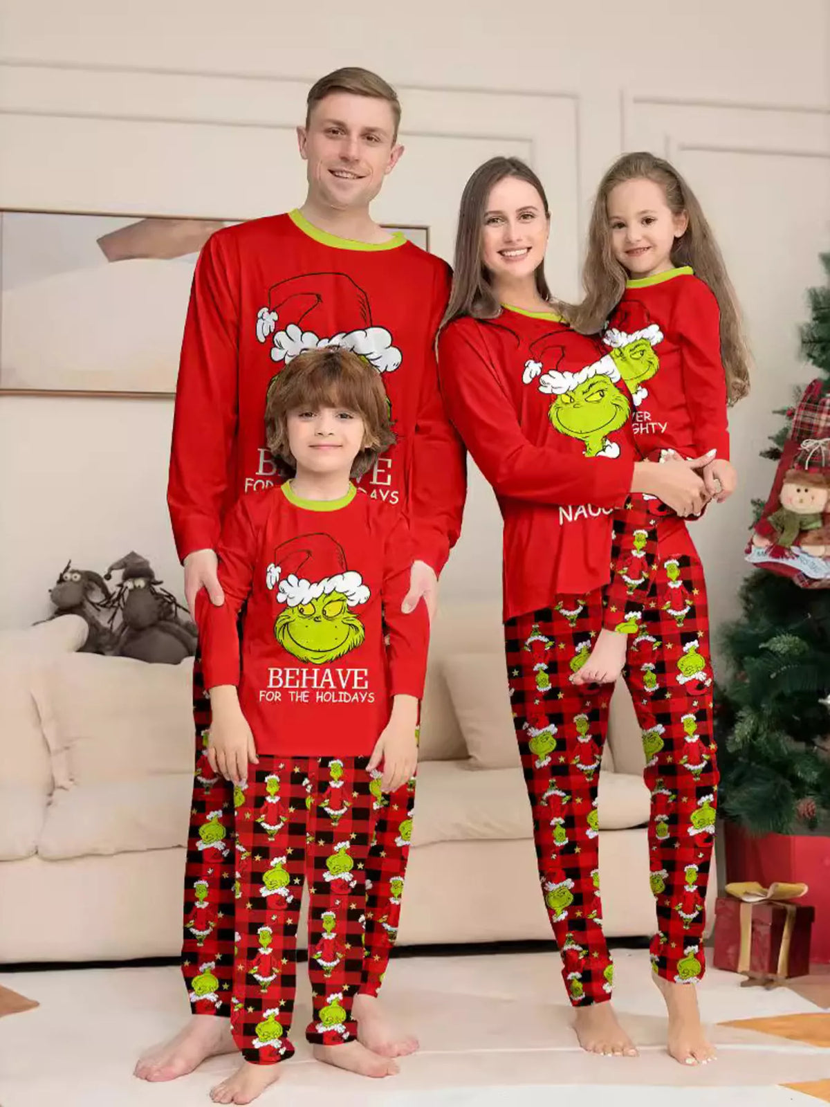 Red matching family Grinch graphic pajama top and Christmas-print pants worn by a family