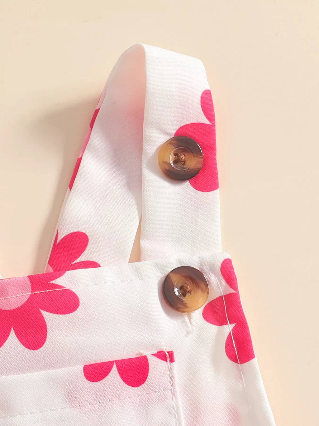 Close-up of the pink-floral overall straps and brown buttons.