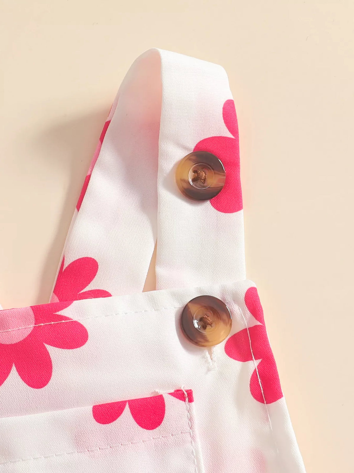 Close-up of the pink-floral overall straps and brown buttons.
