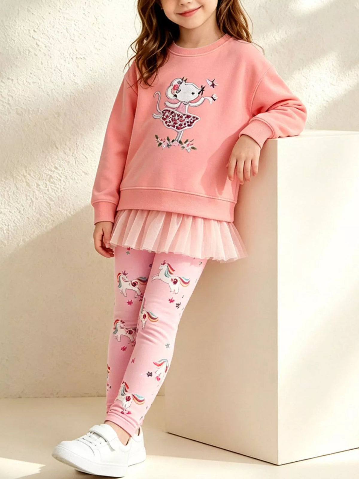 Coral embroidered sweatshirt with ruffle hem and pink printed leggings worn by a child