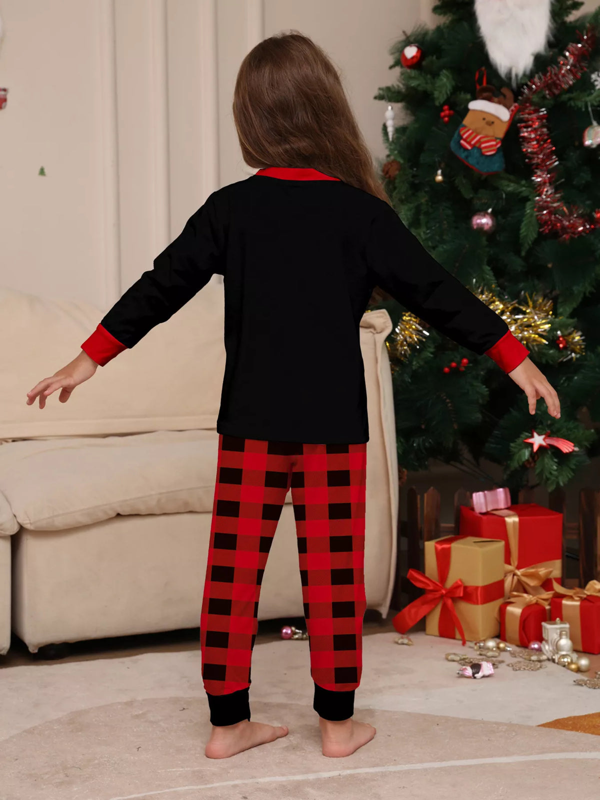 Back view of a child's black pajama top and red plaid pants.