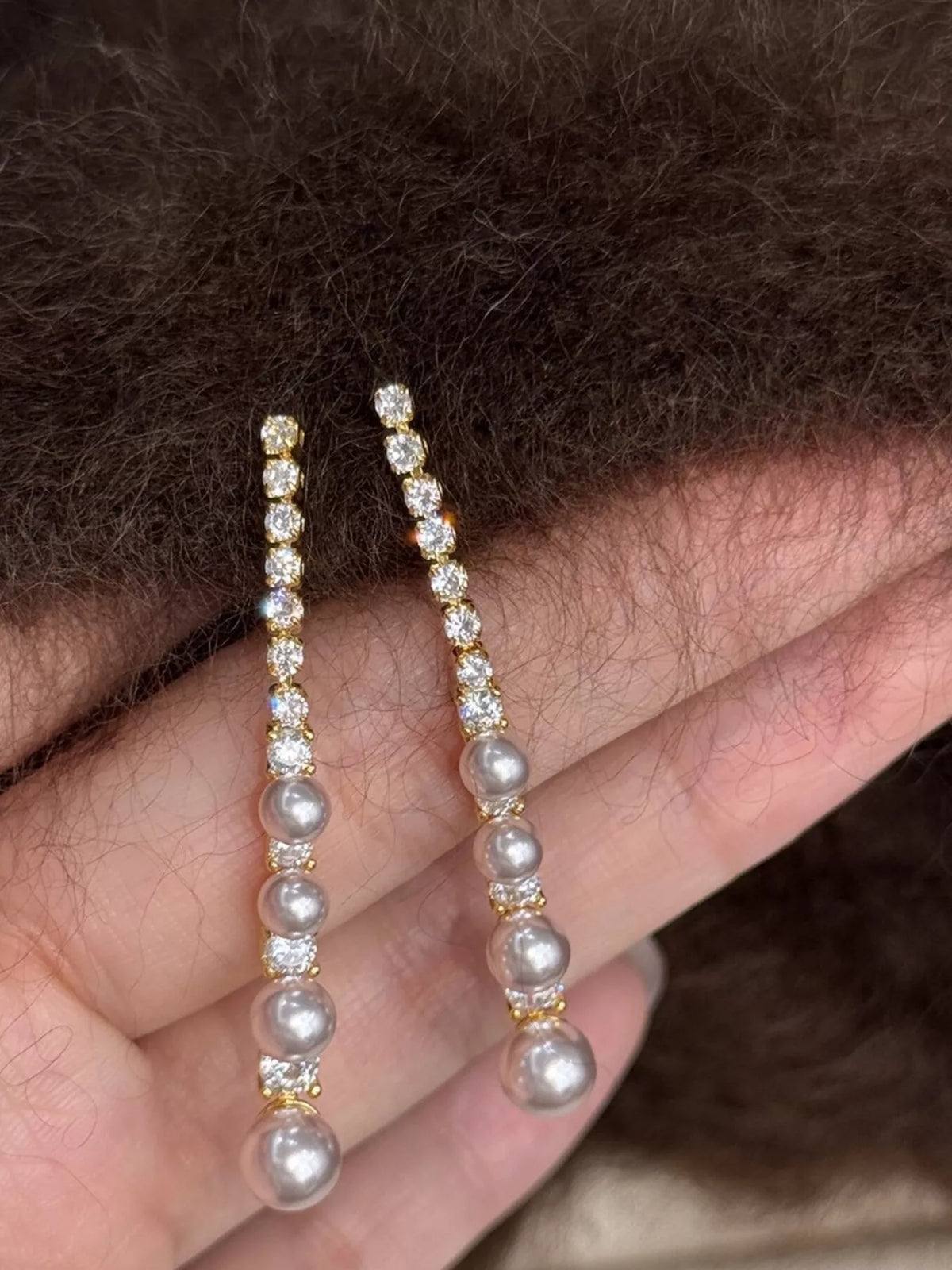 Gold-tone long pearl-like bead and clear stone drop earrings — detail view