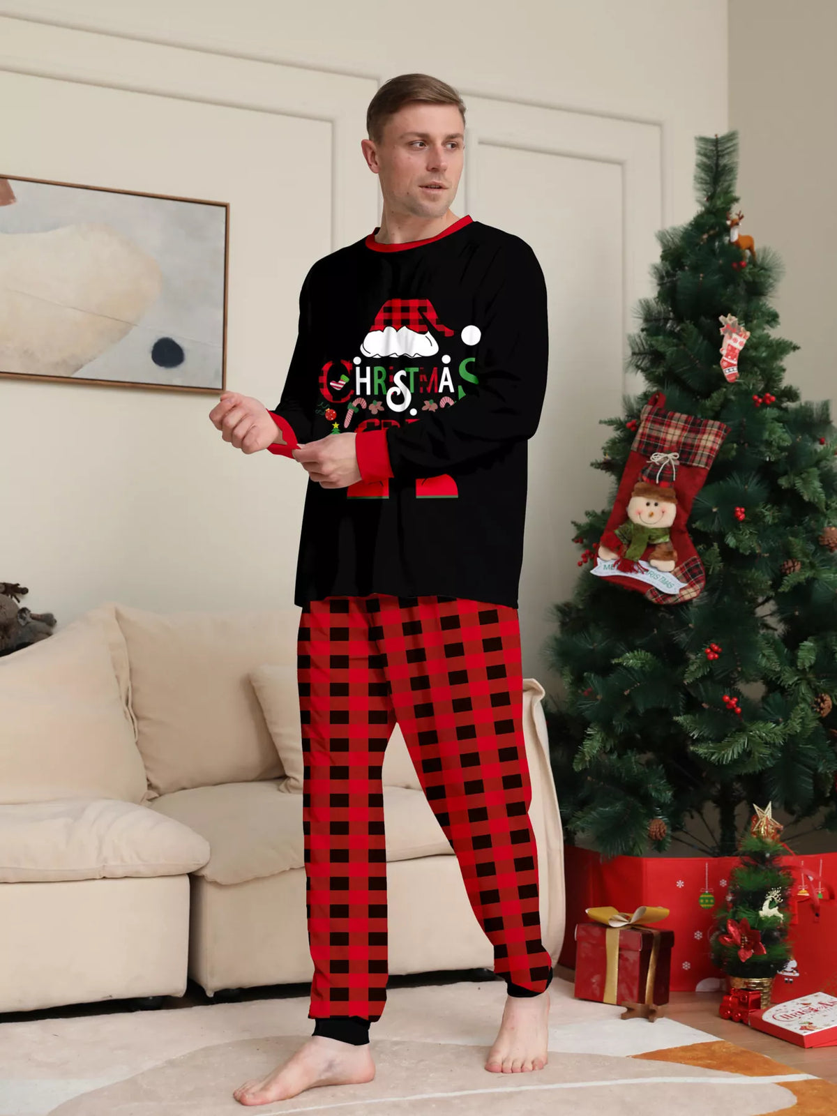 Front view of a man wearing the black Christmas graphic pajama set.