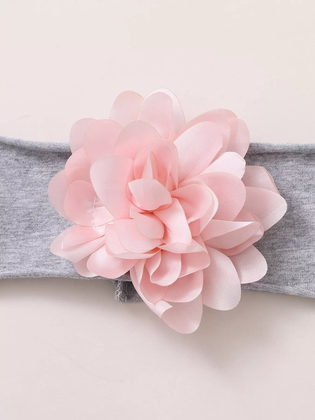 Pink flower attached to a gray baby headband