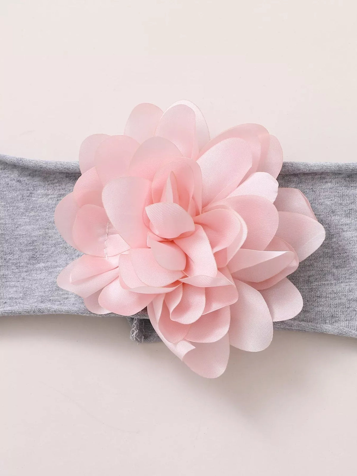 Pink flower attached to a gray baby headband