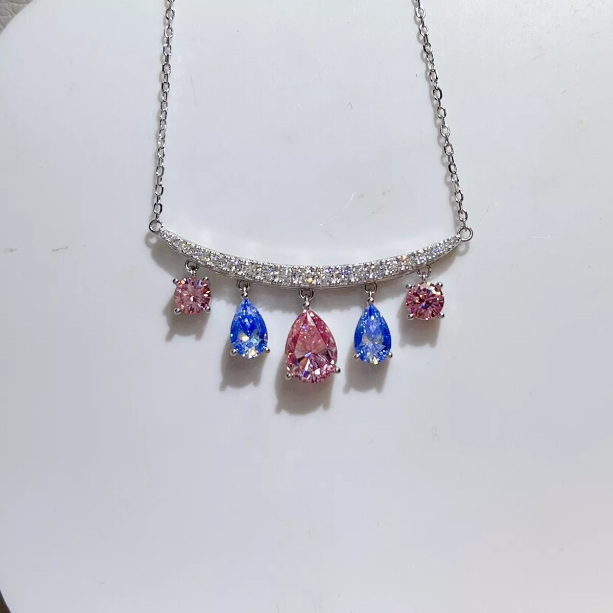 Silver-tone necklace with blue and pink teardrop stone pendants — detail view
