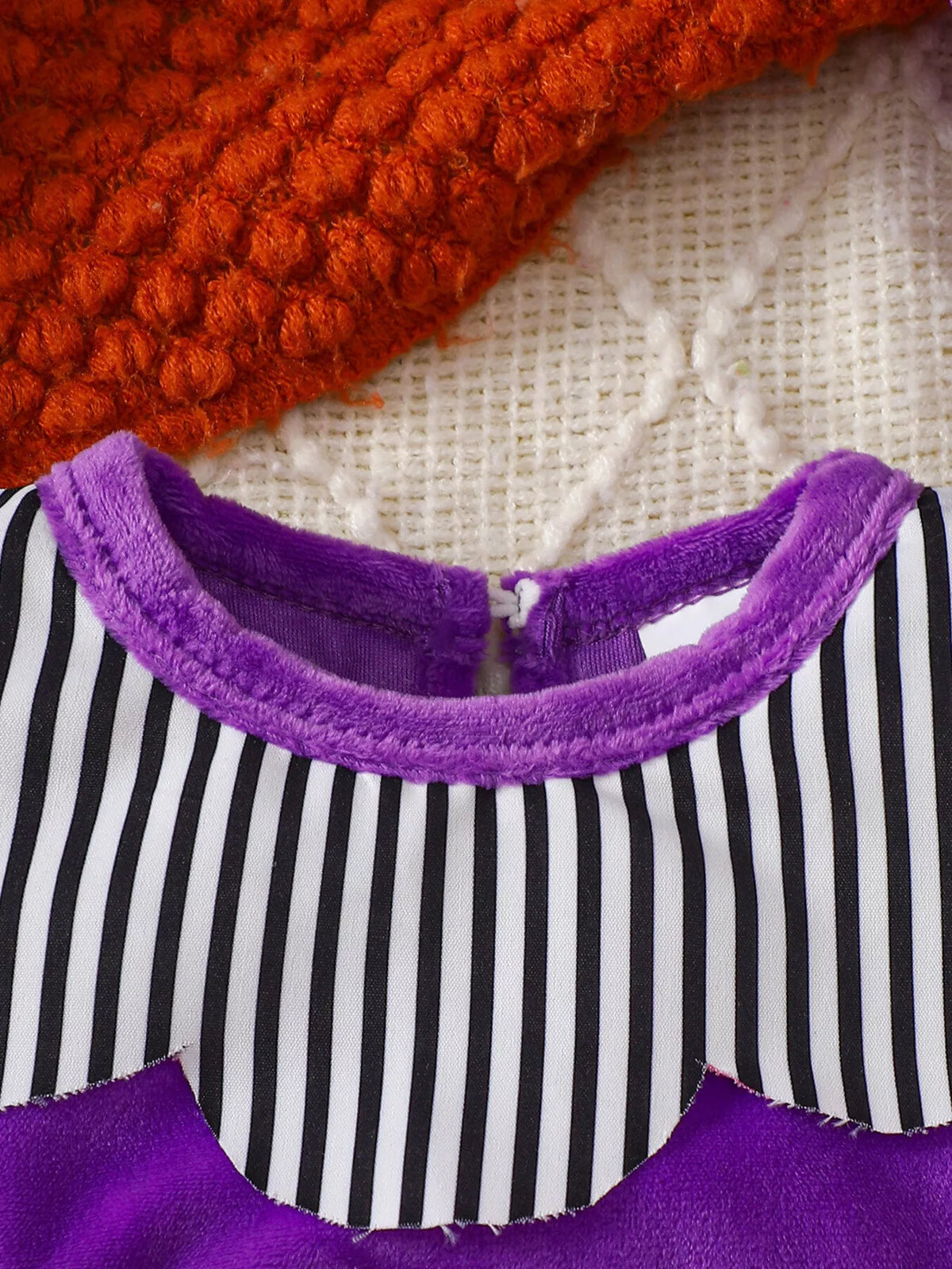 Purple neckline and black and white striped yoke on the baby bodysuit