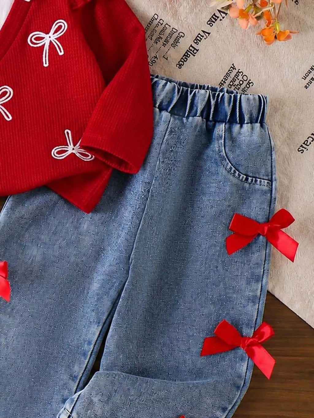 Red bow-embellished sweater beside matching bow-accented blue jeans