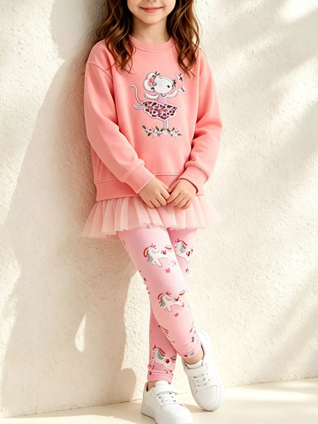 Coral embroidered sweatshirt with ruffle hem and pink printed leggings worn by a child