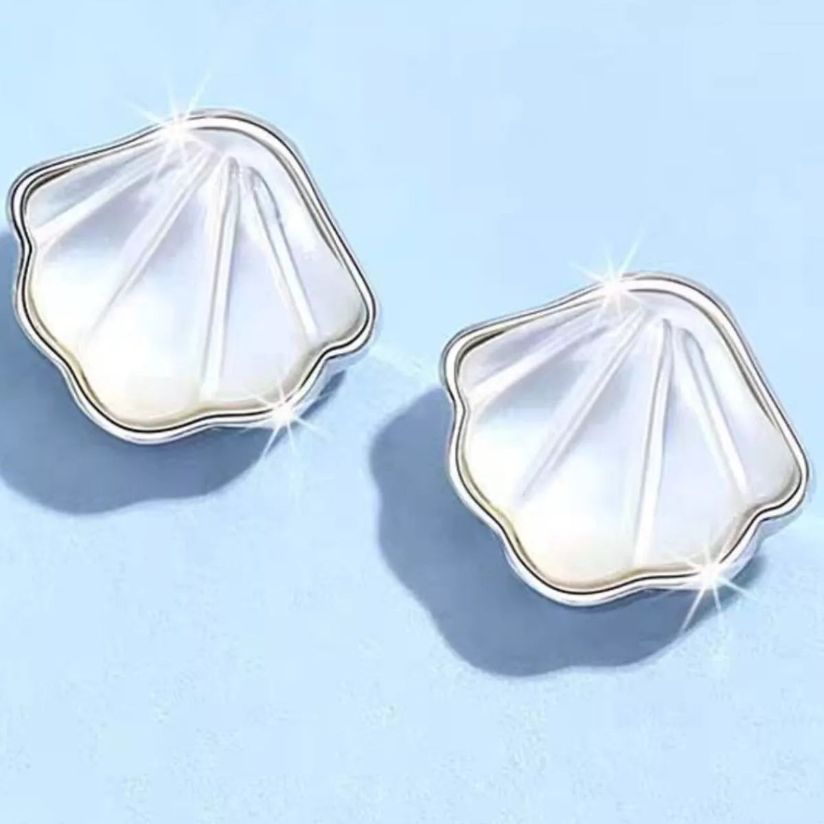 Silver-tone shell-shaped stud earrings with white centers — detail view