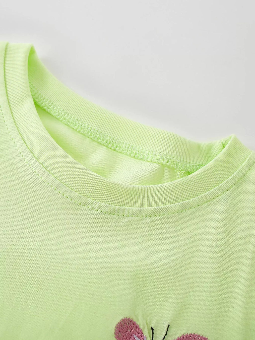 Close-up of the light green top's rounded neckline.