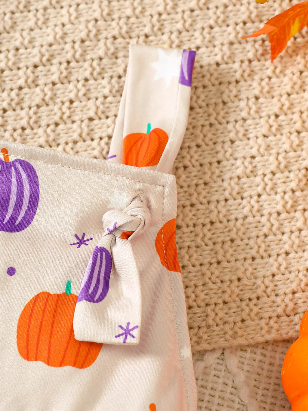Close-up of the pumpkin-print overall strap and button fastening.