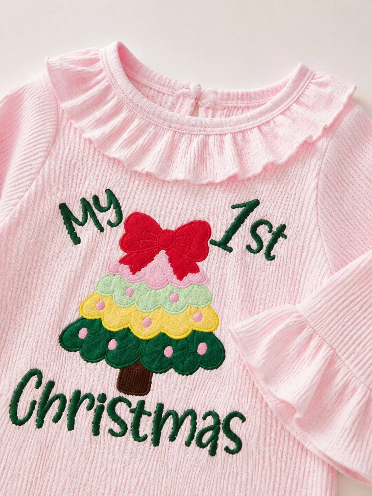 Close-up of My 1st Christmas lettering, red bow and Christmas tree design on the pink romper.