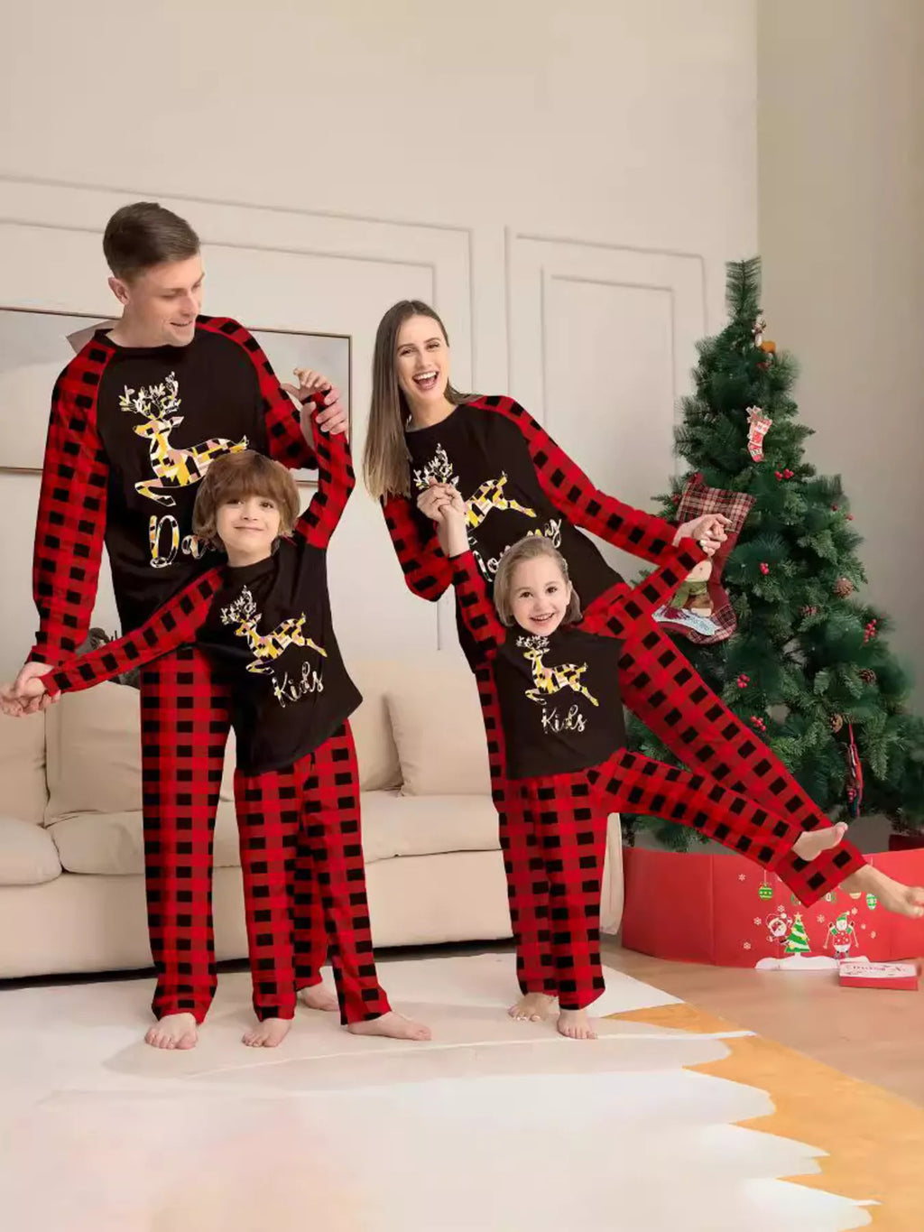 Family modeling matching black reindeer graphic tops with red plaid sleeves and pants.