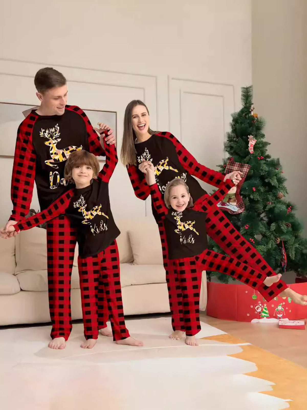 Family modeling matching black reindeer graphic tops with red plaid sleeves and pants.