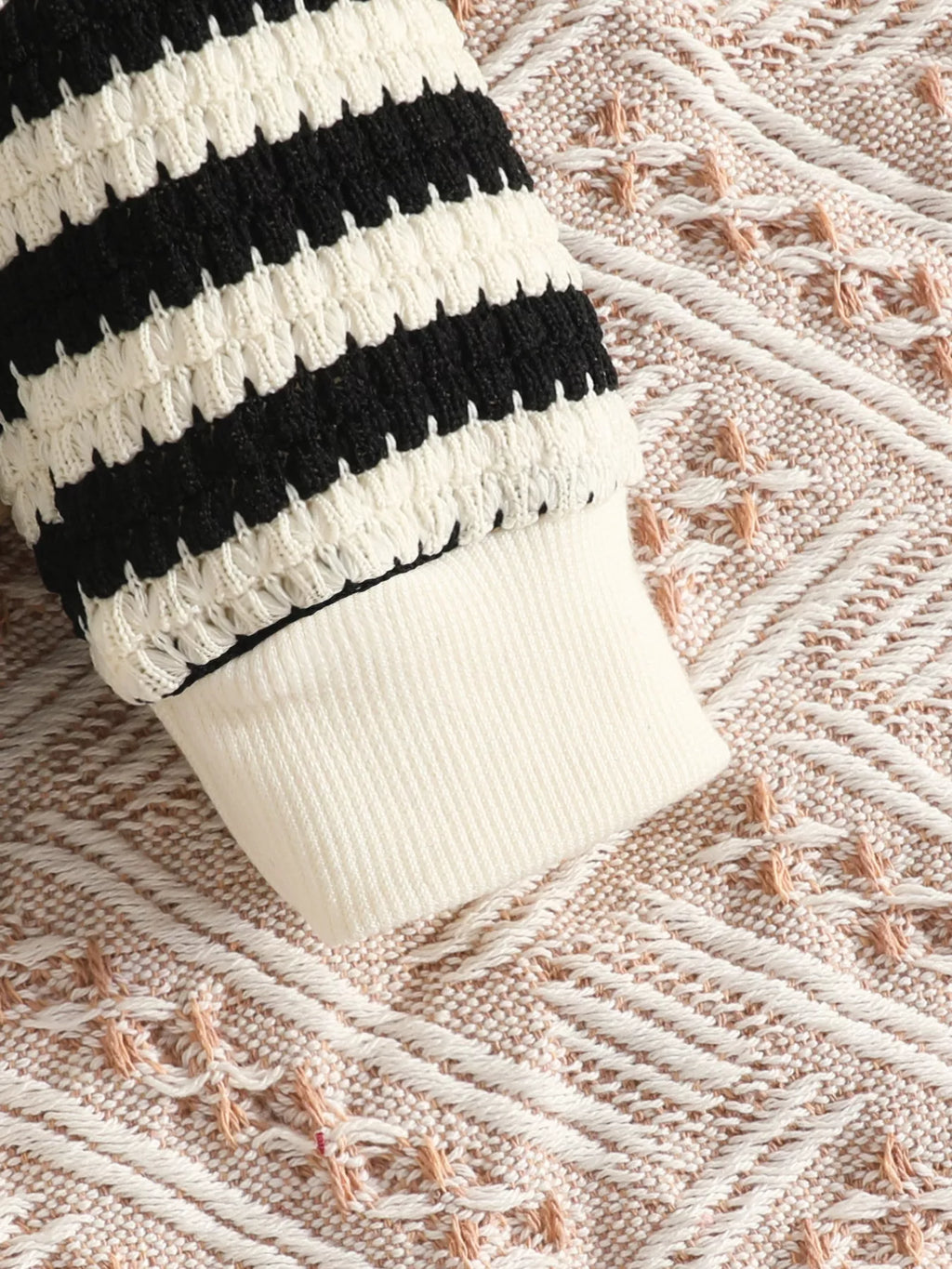 Cream ribbed cuff on the black striped knit top