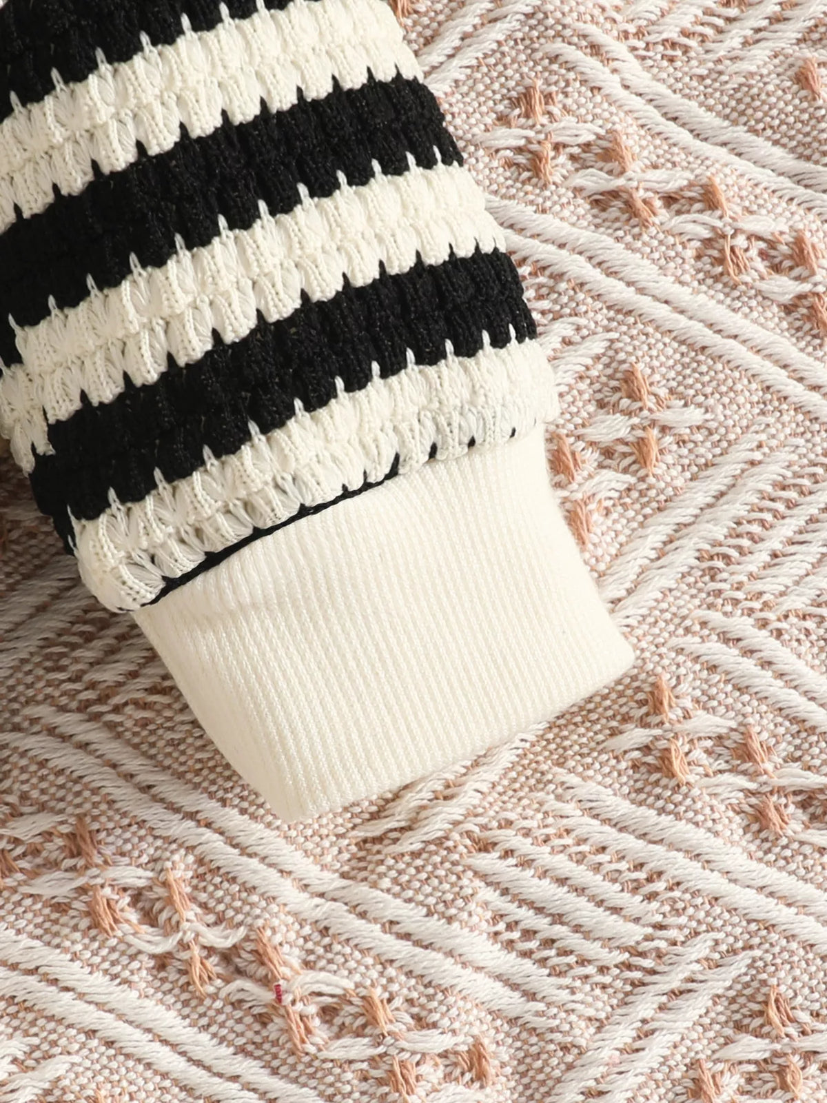 Cream ribbed cuff on the black striped knit top