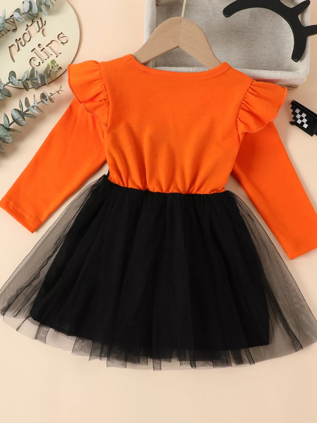 Back view of the orange long-sleeve dress with black tulle skirt.