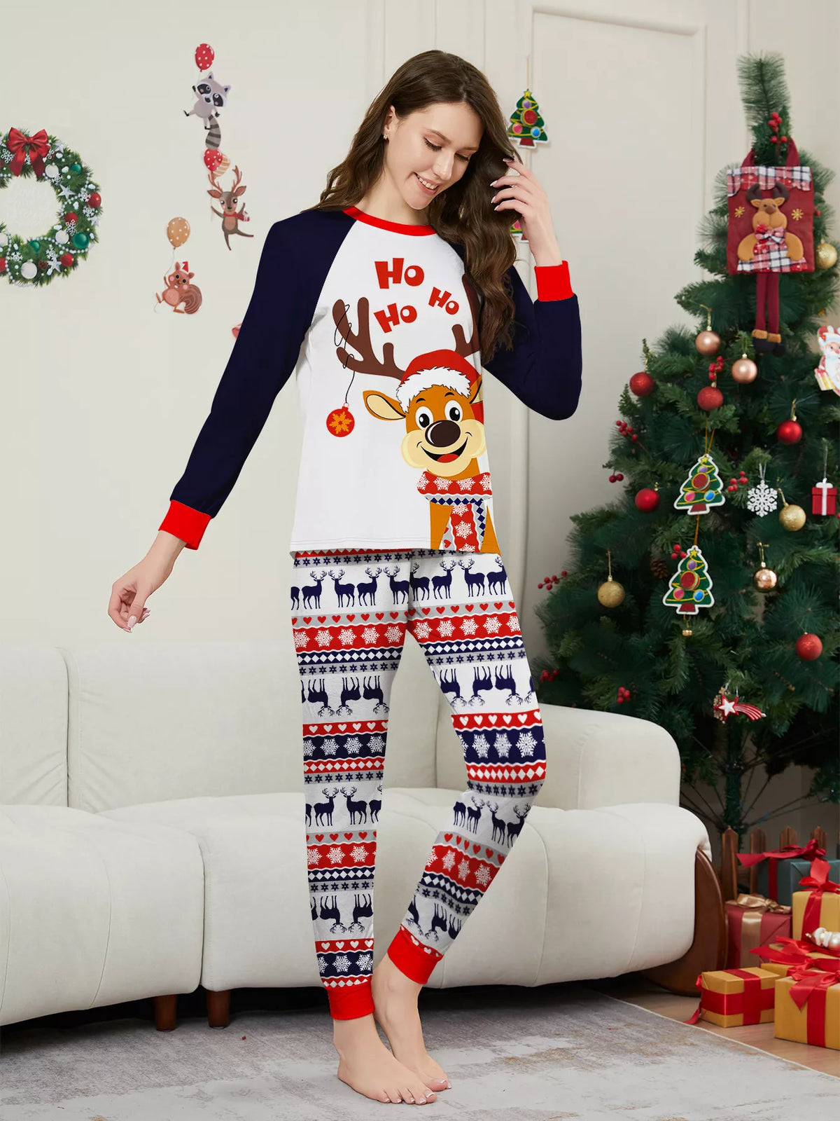 Woman modeling a white reindeer Christmas graphic top with navy sleeves and festive striped pajama pants.
