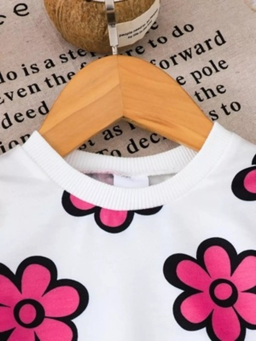 Close-up of the white floral sweatshirt's ribbed neckline.