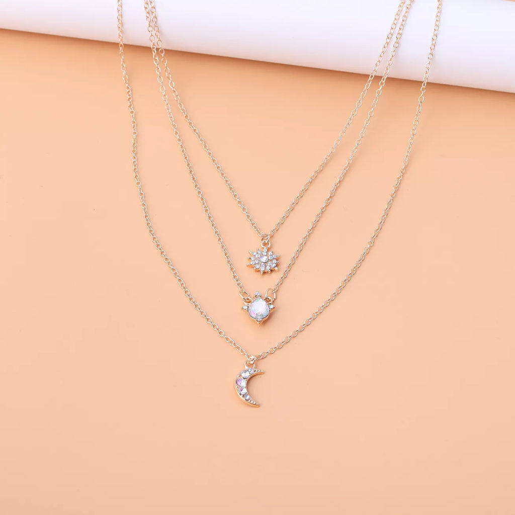 Layered silver-tone necklace with celestial and clear stone charms — detail view