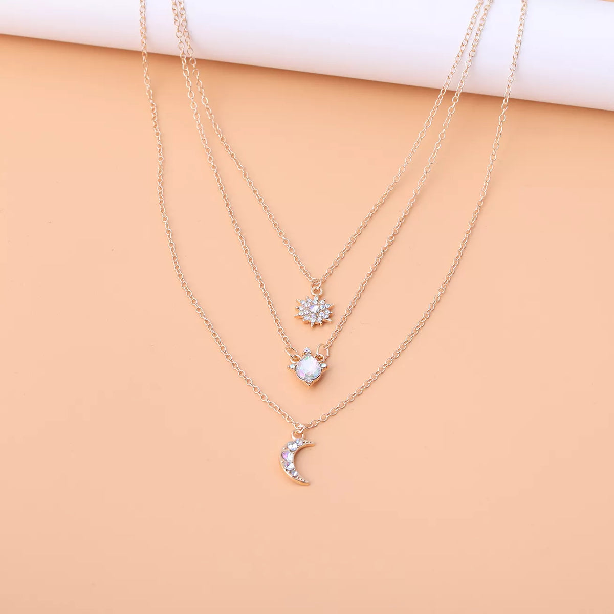 Layered silver-tone necklace with celestial and clear stone charms — detail view