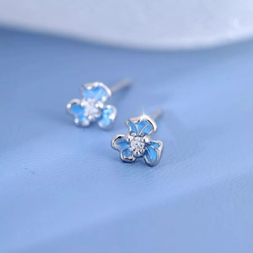 Silver-tone flower stud earrings with blue stones — detail view