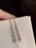 Gold-tone long pearl-like bead and clear stone drop earrings — detail view